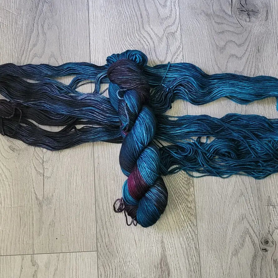 Blue and black yarn skeins on a wooden floor